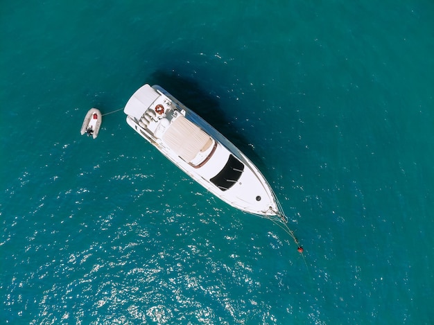 Adorable foto de vista aérea superior de un enorme yate de dos pisos y un pequeño bote junto a él navegando a través del mar azul profundo