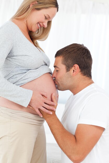 Adorable futuro padre besando el vientre de su esposa