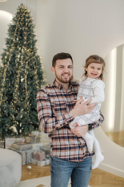 Adorable hija con su querido padre en casa en gront of fit tree chrisrmas mood