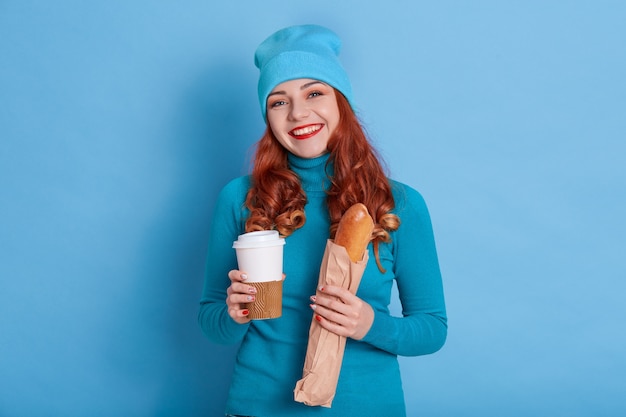 Adorable joven feliz tiene pan largo y café para llevar