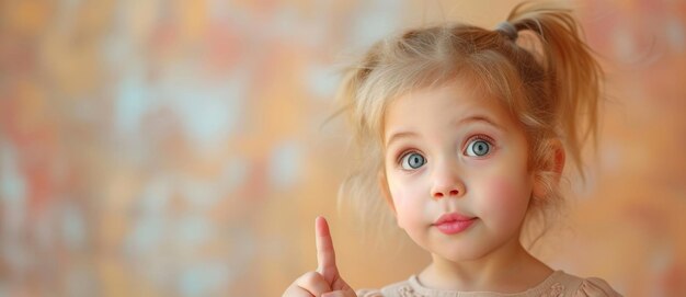 Foto adorable joven con grandes ojos azules apuntando con el dedo hacia arriba y mirando a la cámara de una manera linda y curiosa