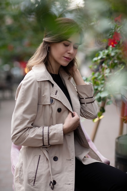 Adorable joven sentada en el café de la calle por la mañana