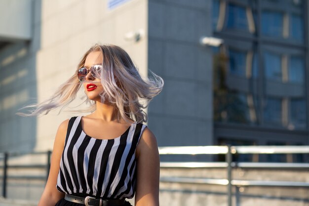 Adorable modelo rubia con gafas, posando con el pelo ondeando