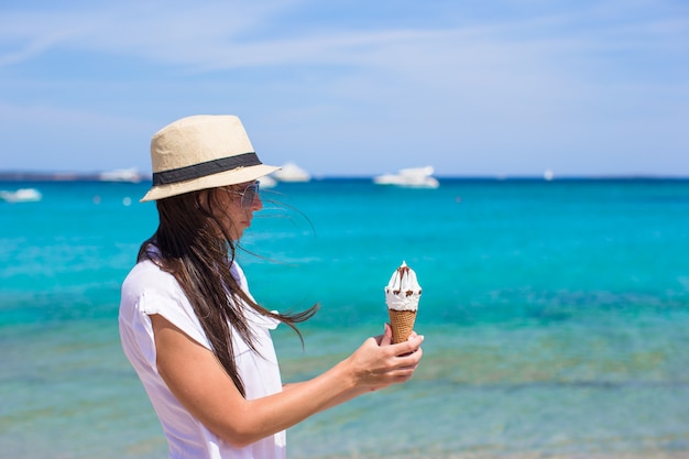 Adorable mujer comiendo helado en playa tropical