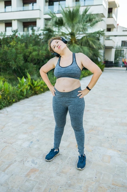 Adorable mujer gorda en chándal se dedica a fitness al aire libre vista lateral retrato copia espacio joven ov