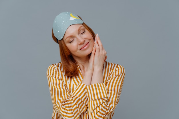 Foto adorable mujer pelirroja pecosa mantiene los ojos cerrados