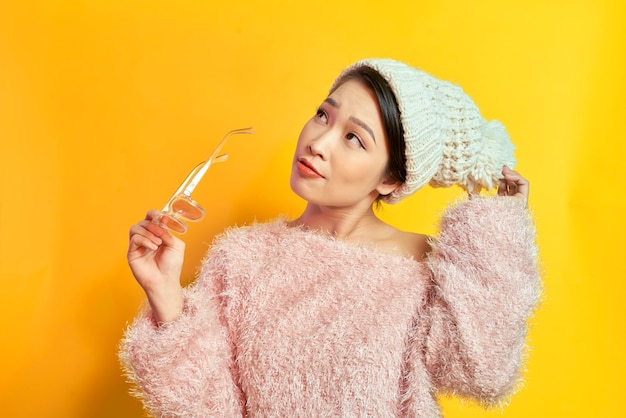 Adorable mujer que expresa verdaderas emociones positivas durante la sesión de fotos en abrigo de piel rosa. Retrato interior de una chica glamorosa activa de pie en pose de confianza y sonriendo.