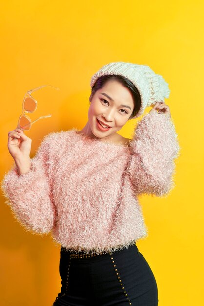 Adorable mujer que expresa verdaderas emociones positivas durante la sesión de fotos en abrigo de piel rosa. Retrato interior de una chica glamorosa activa de pie en pose de confianza y sonriendo.