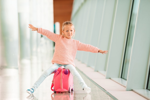 Adorable niña en el aeropuerto con su equipaje esperando el embarque