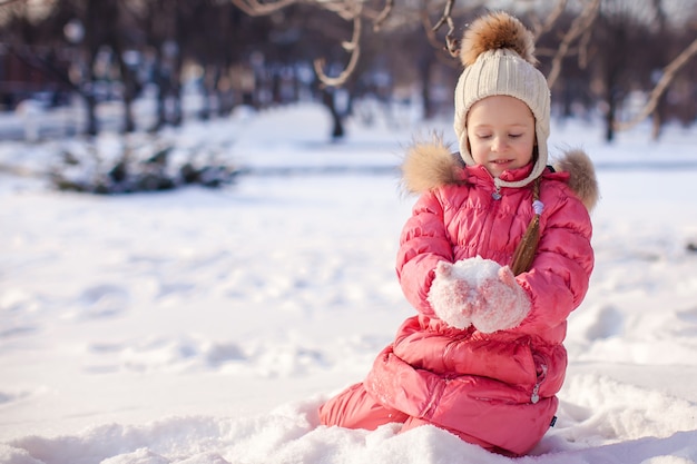 Adorable niña al aire libre en el parque en un frío día de invierno