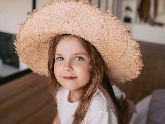 Adorable niña alegre con sombrero de paja en casa interior