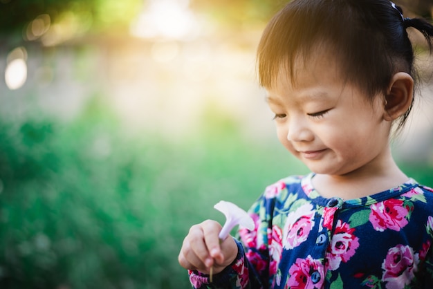 Adorable niña asiática disfruta con césped y flores en el jardín al aire libre