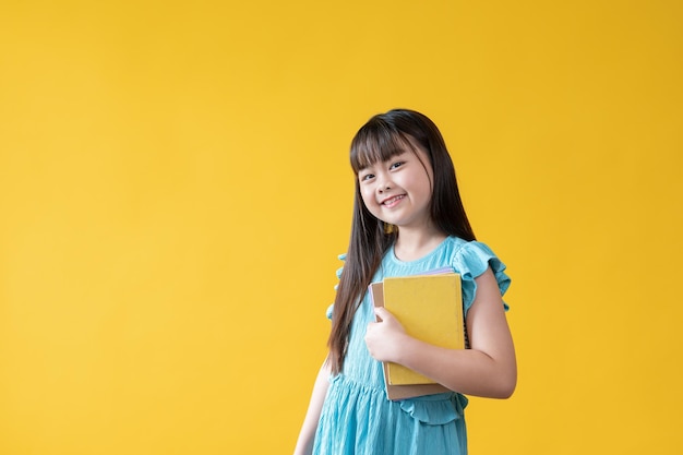 Una adorable niña asiática o una niña de la escuela primaria sosteniendo sus libros