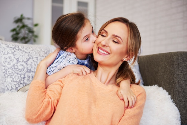 Adorable niña besando a su mami en la mejilla