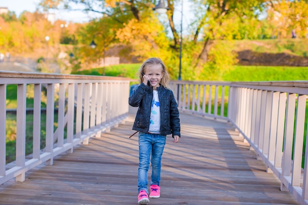 Adorable niña en el cálido día de otoño al aire libre