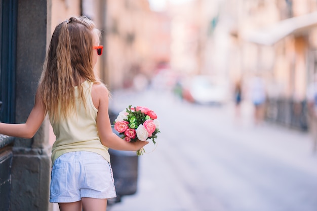 Adorable niña en la calle con ramo de flores