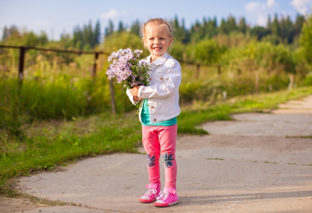 Adorable niña caminando al aire libre con flores