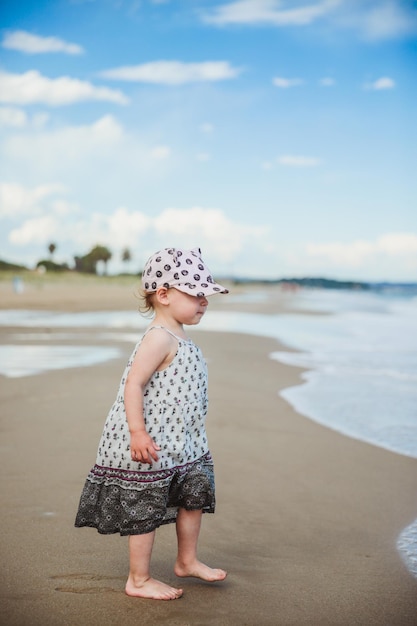 Adorable niña caminando sobre el agua en la playa