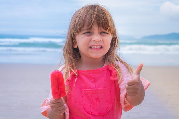 Adorable niña caucásica con una paleta en la playa de vacaciones