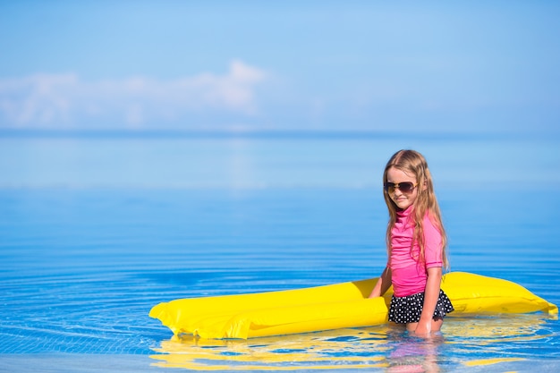 Adorable niña con colchón inflable en piscina al aire libre