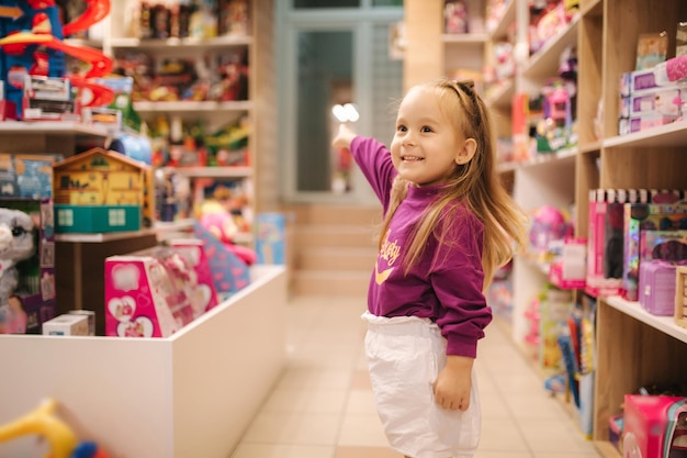 Foto adorable niña comprando juguetes linda mujer en juguetería niña feliz seleccionando juguete