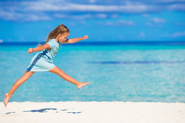 Adorable niña corriendo durante las vacaciones en la playa
