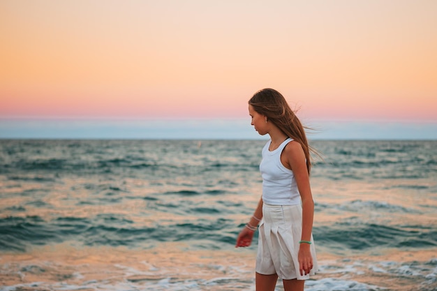 Adorable niña en la costa tropical al atardecer