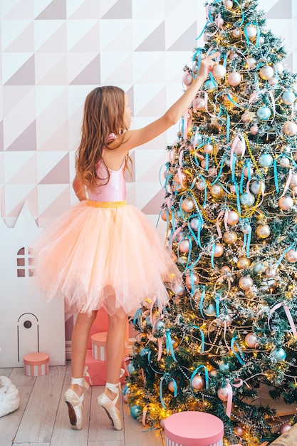 Adorable niña decorando el árbol en el interior