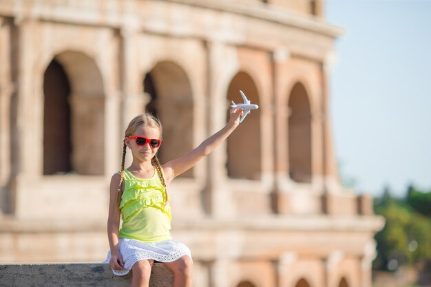 Adorable niña delante del coliseo en roma, italia. niño en vacaciones italianas