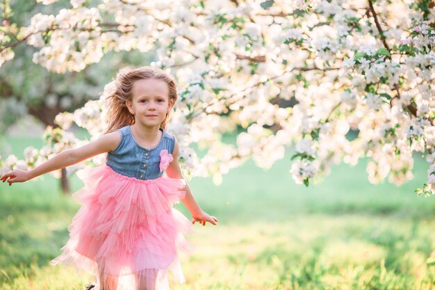 Adorable niña disfrutando el día de primavera en el jardín floreciente de apple