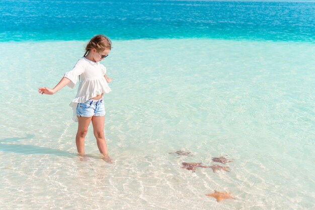 Adorable niña divertirse en la playa tropical durante las vacaciones