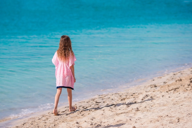 Adorable niña divertirse en la playa tropical durante las vacaciones