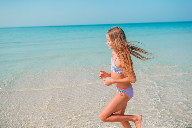 Adorable niña divertirse en la playa tropical durante las vacaciones