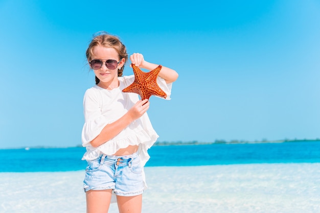 Adorable niña divertirse en la playa tropical durante las vacaciones