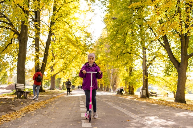 Adorable niña diviértete en el scooter al aire libre