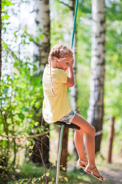 Adorable niña divirtiéndose en un columpio al aire libre