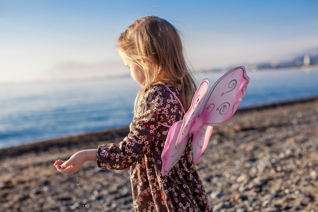 Adorable niña divirtiéndose en la playa en un día soleado de invierno