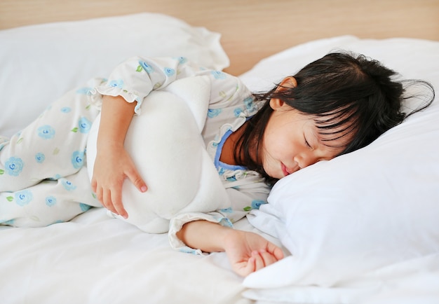 Adorable niña durmiendo en la cama con su juguete