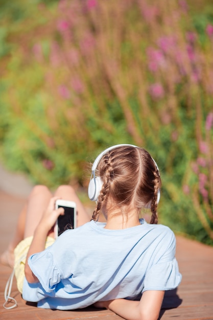 Adorable niña escuchando música en el parque