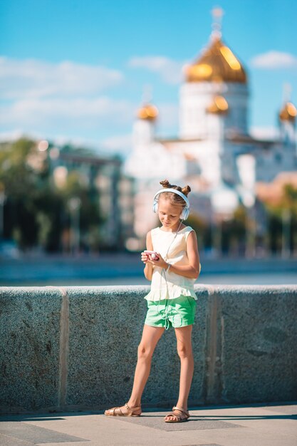 Adorable niña escuchando música en el parque