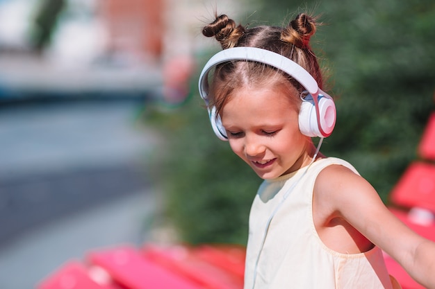 Adorable niña escuchando música en el parque