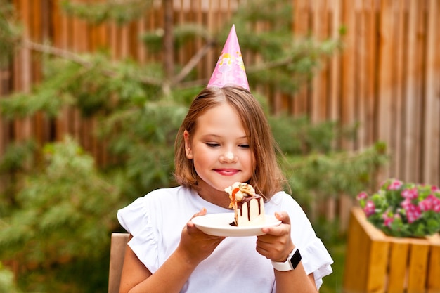 Adorable niña feliz comiendo pastel de cumpleaños en la terraza del café. 10 años celebran cumpleaños.