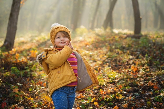 Adorable niña feliz jugando en otoño bosque de cuento de hadas