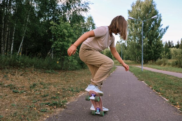 Adorable niña feliz montando patineta en el parque