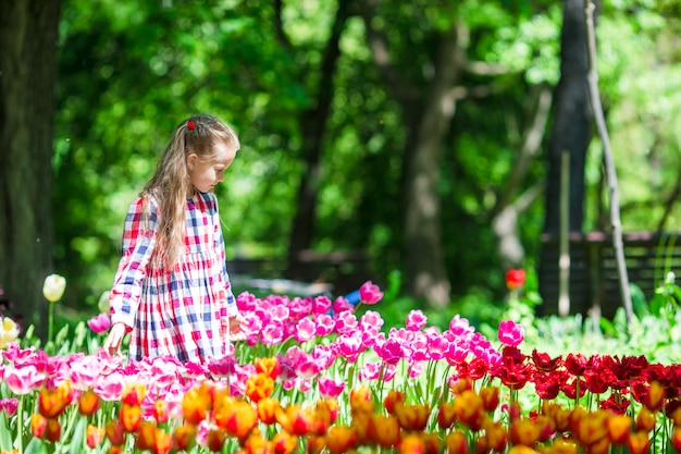 Adorable niña con flores en el jardín de tulipanes