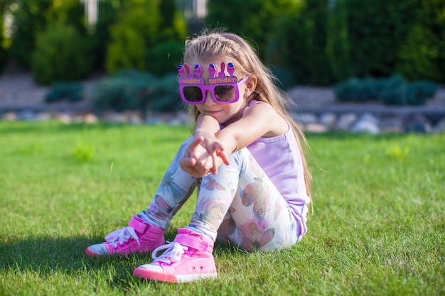 Adorable niña con gafas de feliz cumpleaños sonriendo al aire libre