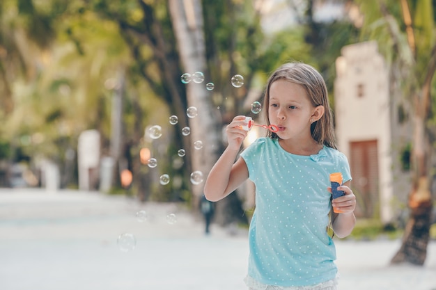 Adorable niña haciendo pompas de jabón durante las vacaciones de verano