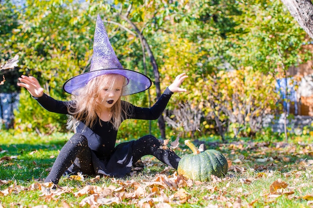 Adorable niña en Halloween que disfraz divertirse al aire libre