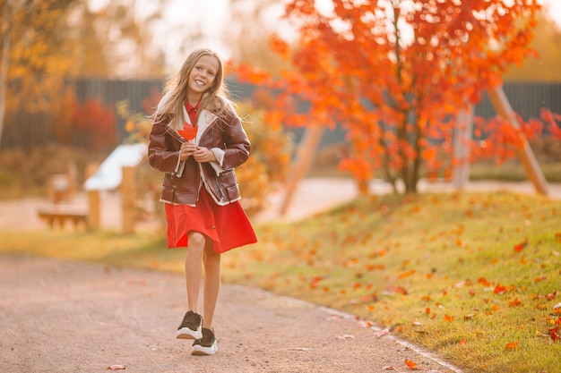 Adorable niña en el hermoso día de otoño al aire libre