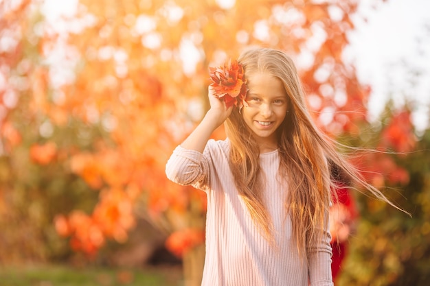 Adorable niña en el hermoso día de otoño al aire libre